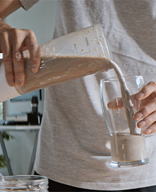 Homem despejando immuno whey essential nutrition em um copo.