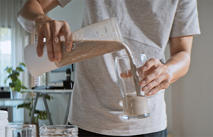 Homem despejando immuno whey essential nutrition em um copo.