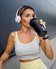  Mulher bebendo immuno whey de uma garrafa de bebida esportiva.