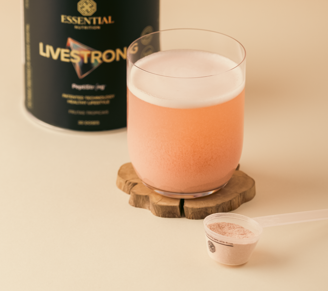 Shake de proteína de chocolate em copo, com chocolate em pó ao lado, destacando a textura cremosa da bebida e ao fundo lata do produto Livestrong.