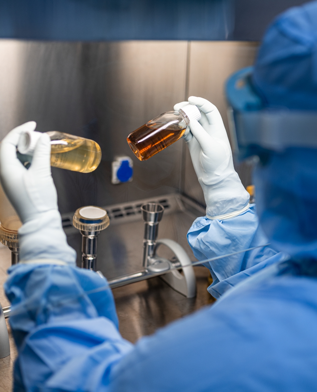 Profissional manipulando medicamentos injetáveis em cabine de fluxo controlado