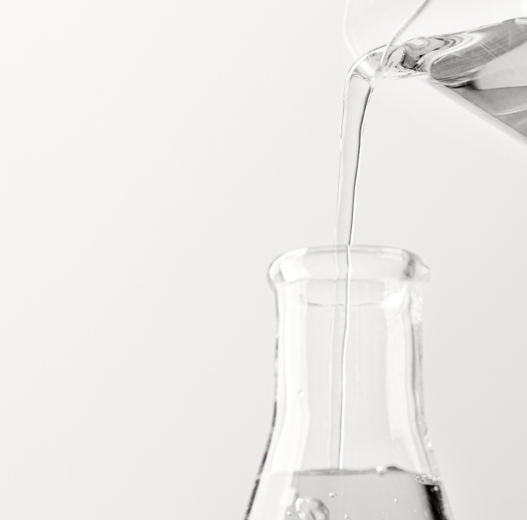 Profissional manipulando solução líquida em vidrarias de laboratório