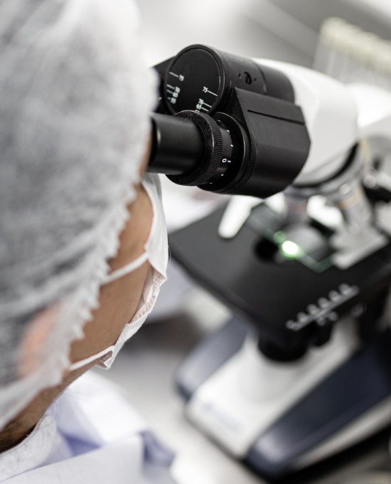 Especialista realizando análise microscópica em laboratório para avaliação da qualidade farmacêutica