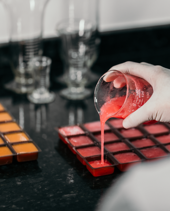 Profissional manipulando solução líquida em vidrarias de laboratório durante processo de análise farmacêutica.