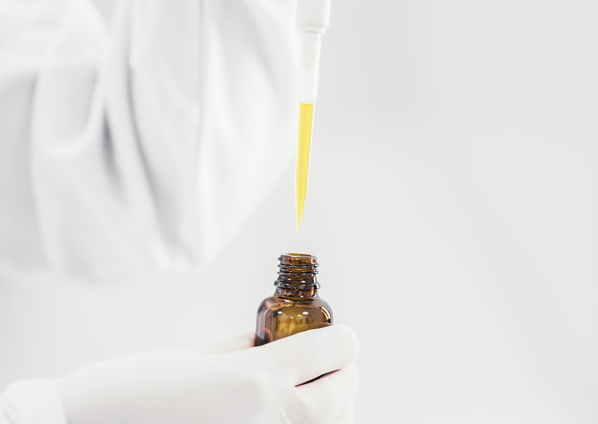 Técnico utilizando micropipeta para transferir amostra para frasco de vidro âmbar em laboratório farmacêutico