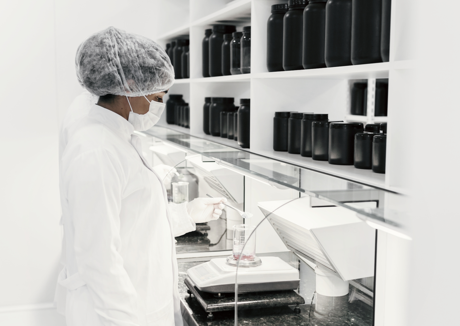 Profissional manipulando solução líquida em vidrarias de laboratório durante processo de análise farmacêutica.